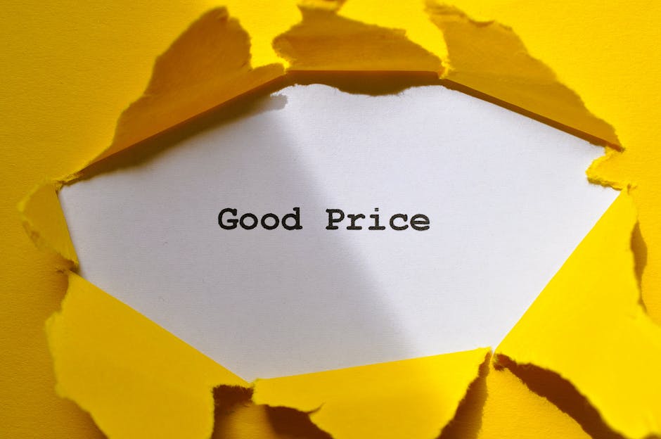 A torn section of yellow paper reveals a white inner surface with the phrase 'Good Price' printed in black text. The torn edges of the paper are jagged and irregular, exposing the clean, smooth white surface beneath. The background is predominantly yellow, matching the torn outer layer, and the image creates a visual connection to packaging or packing materials used during home relocation. The setting suggests a focus on transparent pricing and hidden removal fees, relevant to the services of Removal Van Marylebone, which specializes in removals and furniture transport. The lighting is even, highlighting the textured torn paper and the clear message on the white surface, emphasizing clarity and straightforwardness in moving quotes.